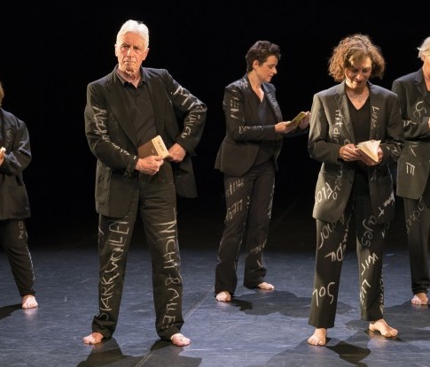 Bühnenaufnahme von Worte bewegen Menschen. Vier ältere Männer und Frauen in schwarzen Anzügen, beschrieben mit weisser Kreide.