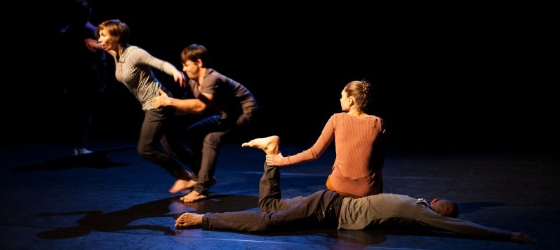 Vier Tänzerinnen und Tänzer bewegen sich in zwei verschiedenen Positionen auf der Bühne.