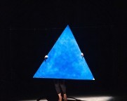 Eine Person verdeckt von einem grossen blauen Dreieck